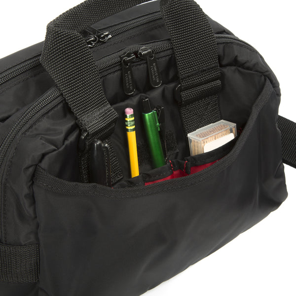 Black bag with compartments containing stationery items on a white background
